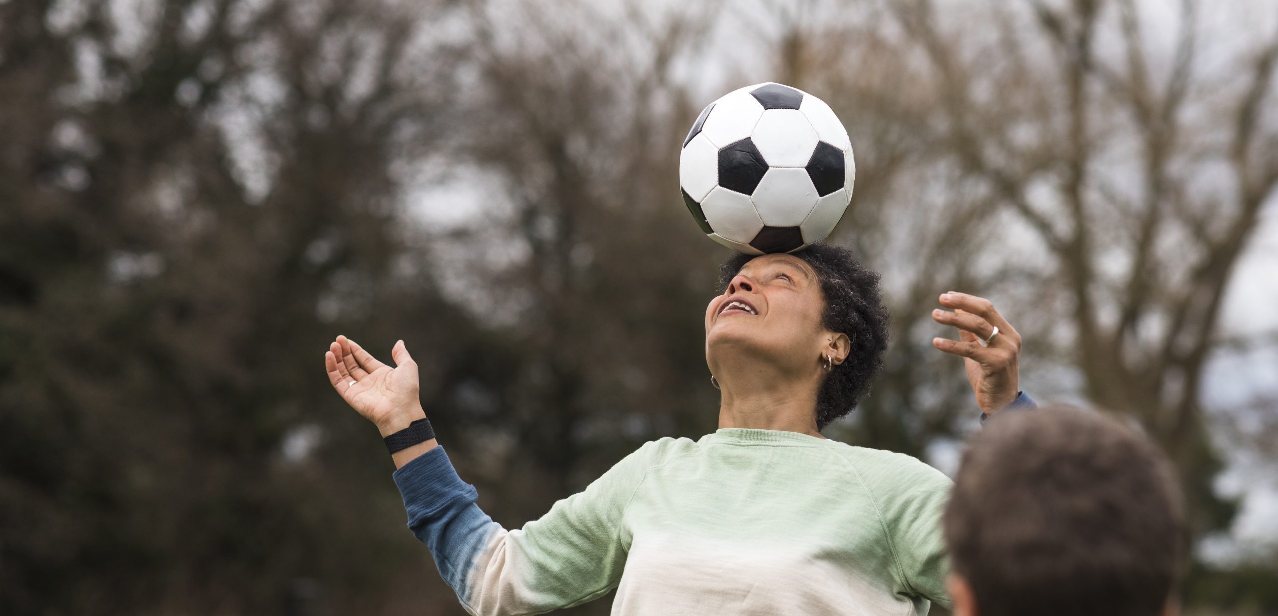 Black woman aged 45-55 playing football with her sun