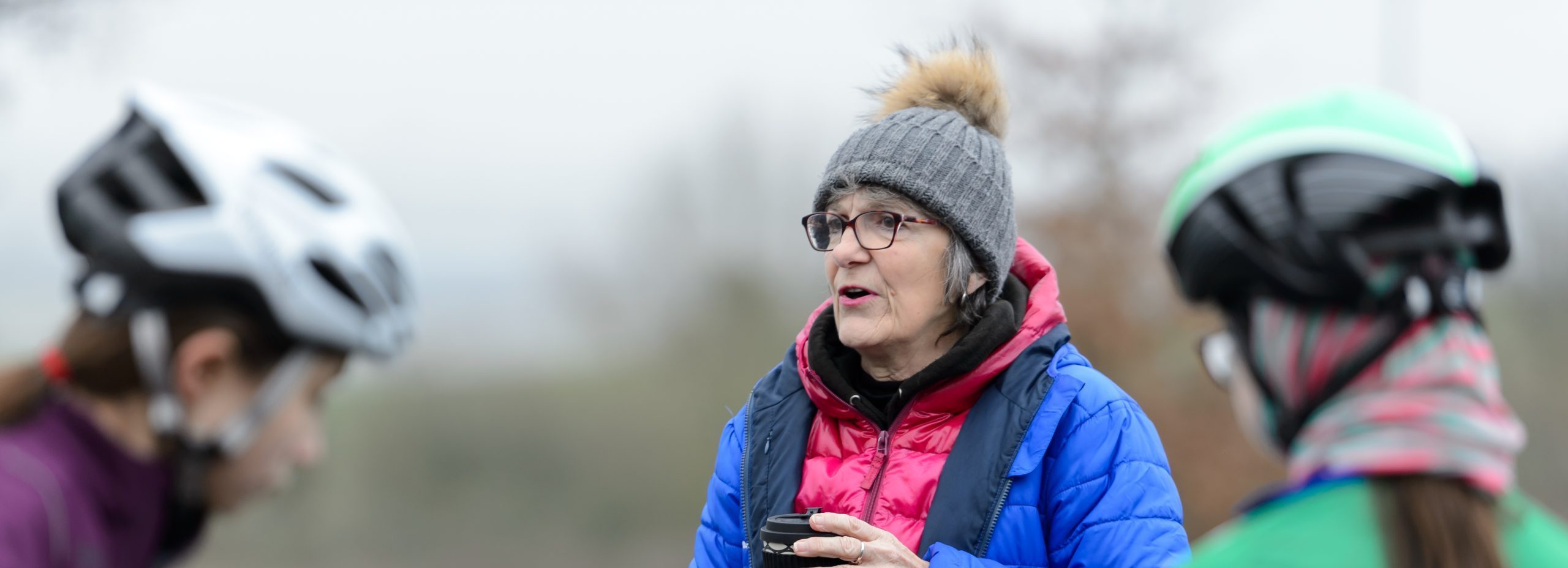 White cycling coach aged 50-60 speaking to two young female cyclists