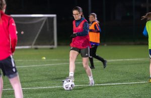 A young woman playing football at night