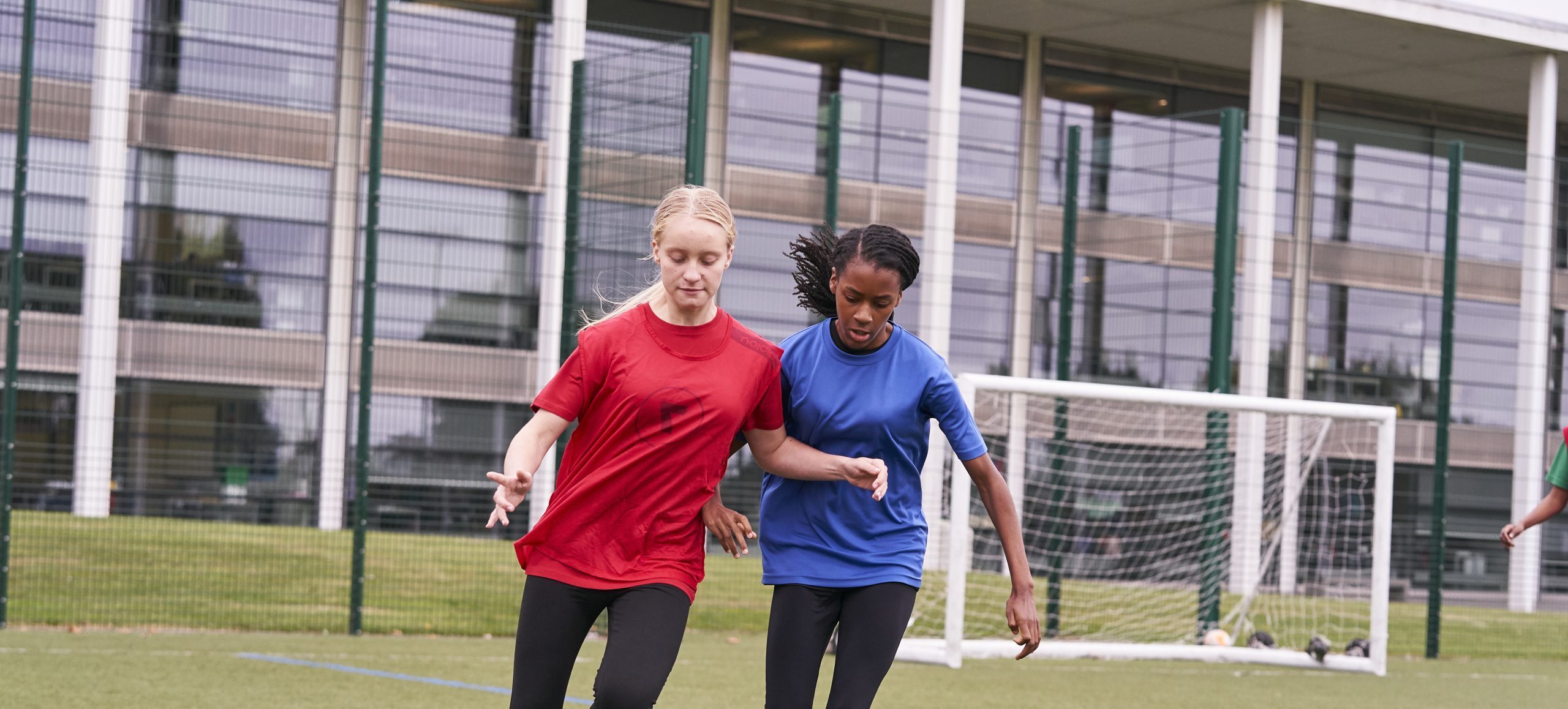 Two teenage girls playing football.