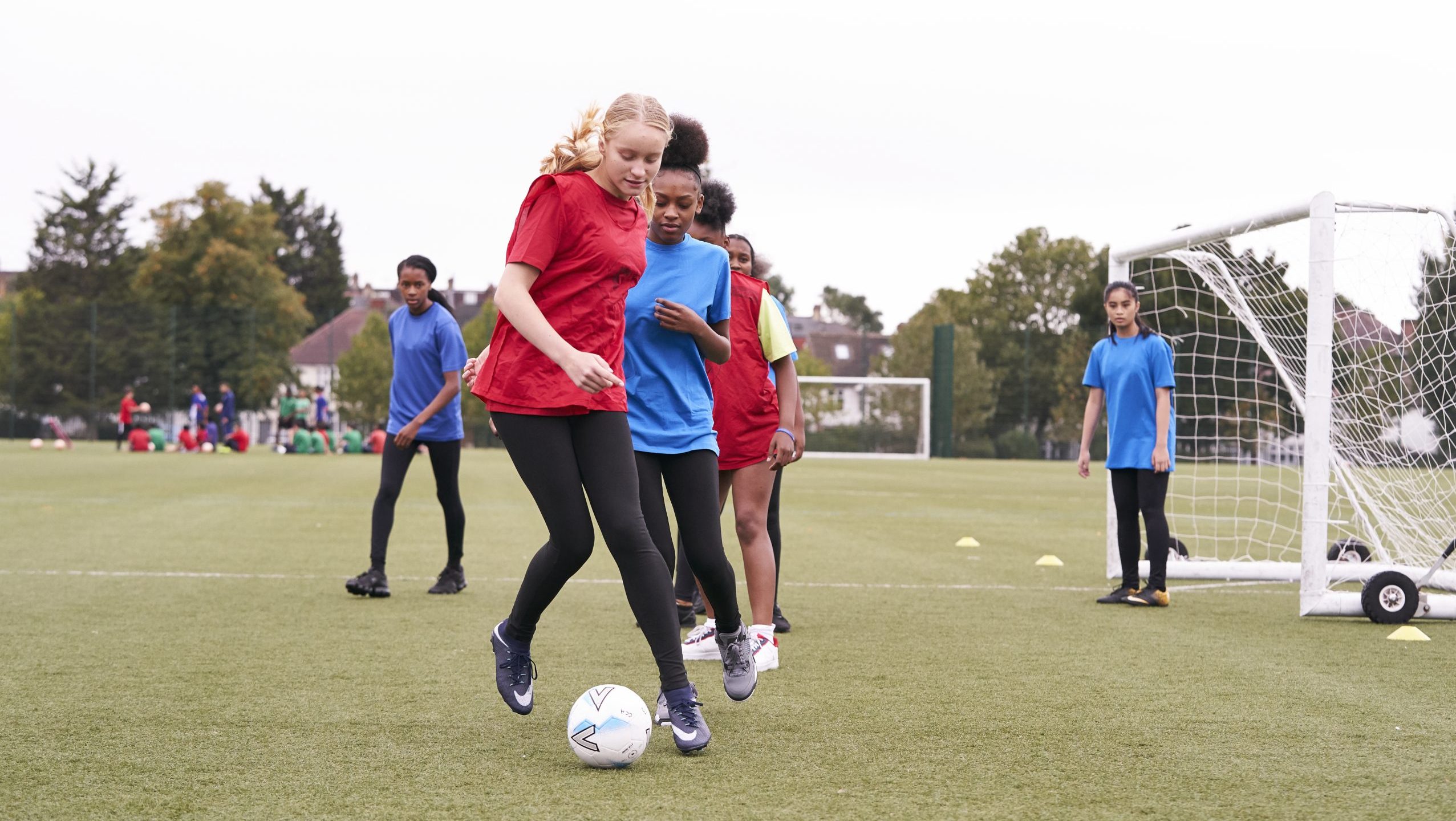 Teenage girls playing football on the school field