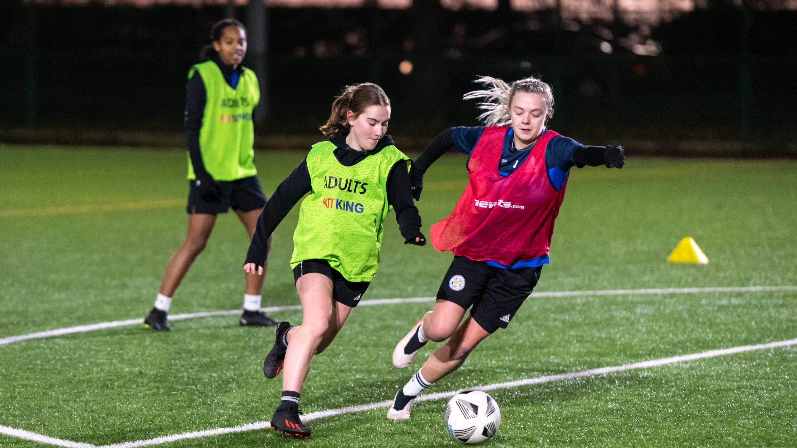 Two young women playing football at night