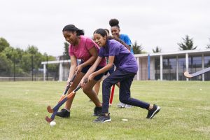 A group of teenage girls from different backgrounds playing hockey